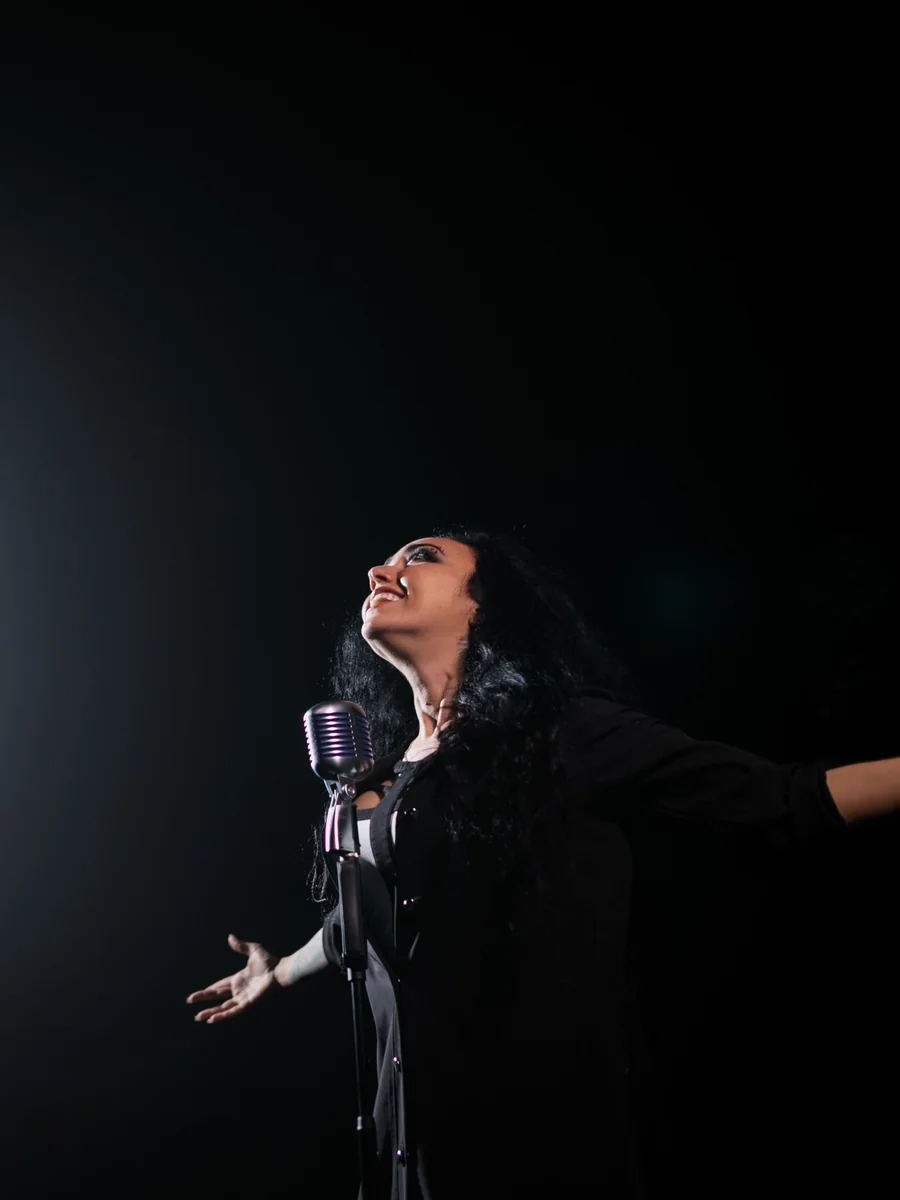 A flamenco singer performing passionately under a stage spotlight against a dark background (representative photograph, not Corral de la Morería's own cast)